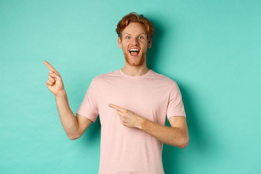 Cheerful caucasian man in t-shirt looking happy, pointing fingers left and showing promo offer, standing over turquoise background.