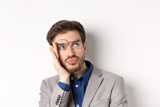 Close-up of shocked tired office worker takes-off glasses and stare at upper right corner with sad face, white background.