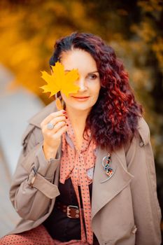 Beautiful girl walking outdoors in autumn. Smiling girl collects yellow leaves in autumn. Young woman enjoying autumn weather