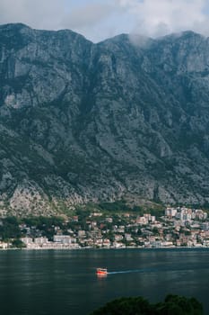 Boat sails along the bay against the backdrop of the old town at the foot of the mountains. High quality photo