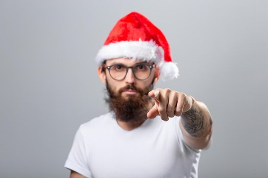 Holidays and people concept - Portrait of a handsome brutal man in Christmas hat. Over grey background