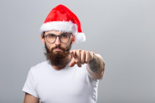 Holidays and people concept - Portrait of a handsome brutal man in Christmas hat. Over grey background