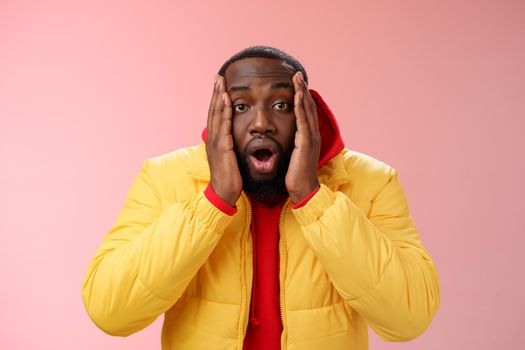 Shocked amazed impressed handsome african bearded guy drop jaw gasping astonished press palms cheeks witness surprising unexpected event, standing speechless stupor pink background. Copy space