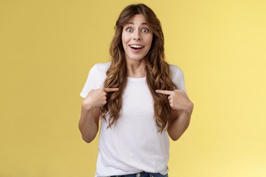 Surprised relieved pleased cute curly-haired girl receive promotion pointing herself lucky smile look camera astonished happily react awesome surprise indicating hopeful delighted yellow background.