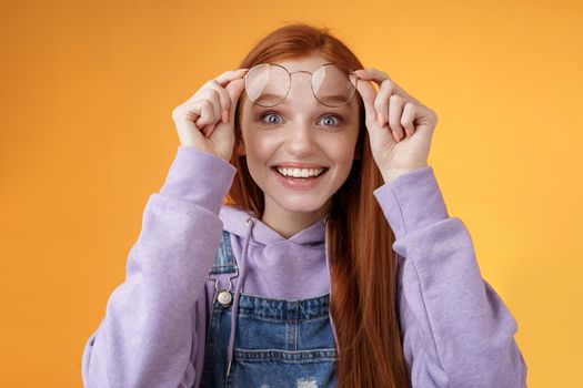 Impressed excited happy pleased young silly lovely redhead girl receive pleasing surprise take off glasses wide eyes touched smiling delighted gasping amazed feel upbeat thrilled. Copy space