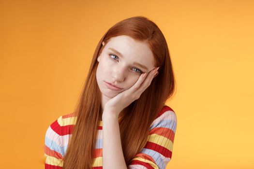 Indifferent careless sleepy redhead silly female student lean palm looking bored uninterested listen lame stories wanna escape standing exhausted lacking interest, posing orange background.