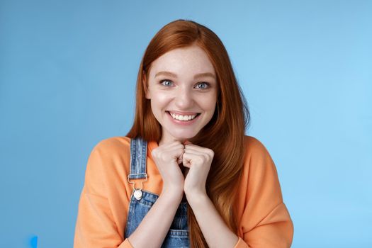 Cute attractive excited smiling happy redhead girl blue eyes freckles receive awesome opportunity study abroad grinning rejoicing very grateful look thankful surprised camera, blue background.