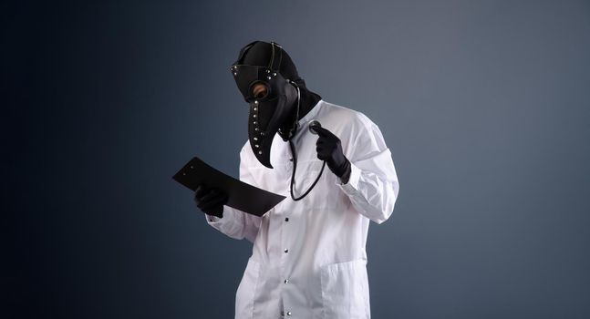 doctor in a dressing gown wearing a plague doctor mask with a stethoscope in his hands