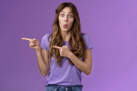 Amused surprised enthusiastic cute girlfriend wanna try advertising product folding lips excited look admiration excitement stand purple background curious interested what located direction.