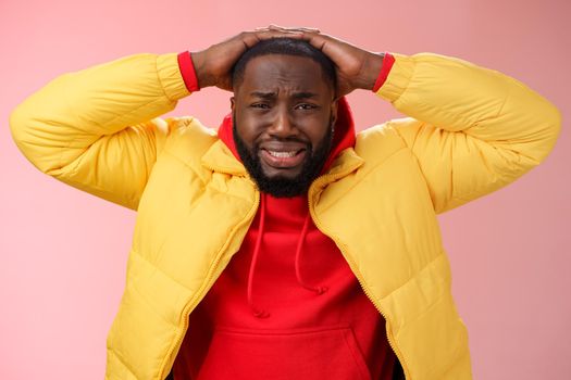 Upset unhappy african-american male entrepreneur lose money feel regret sadness grimacing painful heartbreaking feelings, holding hands head depressed devastated, standing pink background.