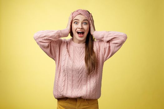Frustrated girl in panic, screaming grabbing head yelling troubled and scared, staring with buged eyes concerned, feeling nervouse, insecure, shouting frightened and worried against yellow background.