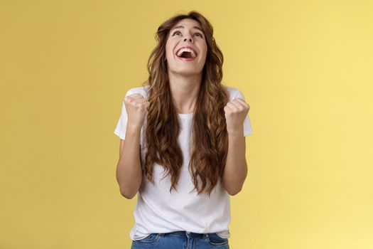 God finally yes. Relieved thankful pleased happy girl look up thank god fist pump celebration success win triumphing clench arms grateful delighted lucky opportunity stand yellow background.