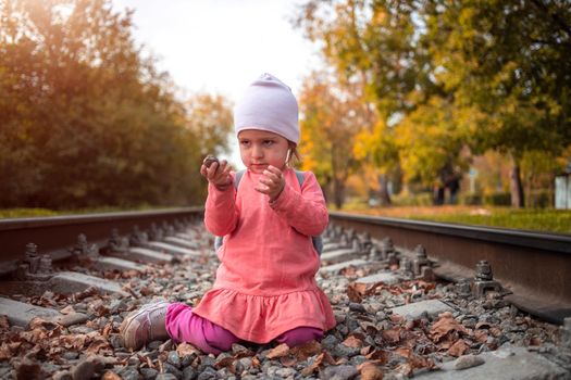 toddler plays on railroad alone autumn day