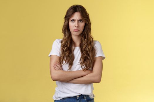 Upset jealous moody clingy girlfriend sulking offended cross hands chest blocking pose frowning disappointed complaining unfair treatment stand yellow background bothered pouting childish.