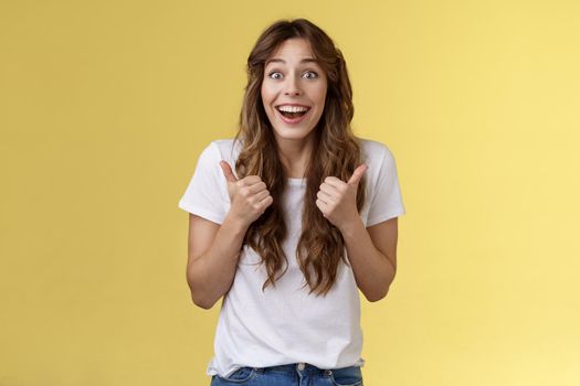 Lively excited happy cute european girl supportive give positive reply think event awesome smiling broadly show thumbs-up approval, accept great choice stand yellow background thrilled.