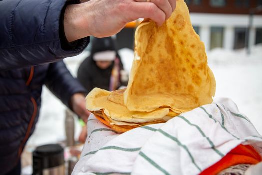 russian blili outdoors on celebration maslenitsa. faceless people take pancakes during Shrovetide at Russia