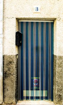 Beniarda, Alicante, Spain- November 26, 2021:Blue and white Striped metal curtain on door in Beniarda village, Alicante, Spain
