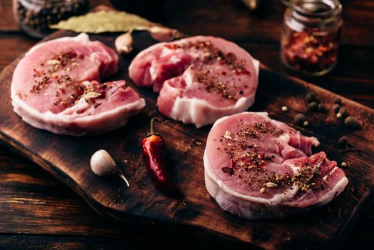 Pork loin steaks with ground spices on rustic cutting board