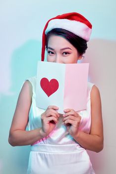 Image of happy beautiful female reading romantic postcard with big red heart,