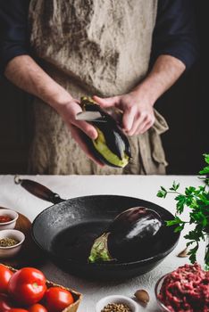 Preparing eggplants for baking and stuffing with ground beef and tomatoes