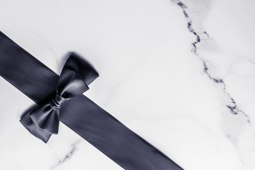 Holiday gift, decoration and sale promotion concept - Black silk ribbon and bow on marble background, flatlay