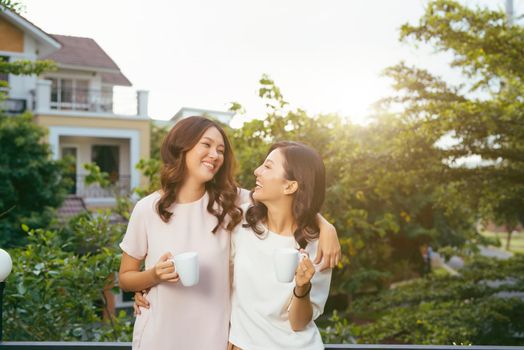 Two Women Relaxing On Rooftop Garden Drinking Coffee