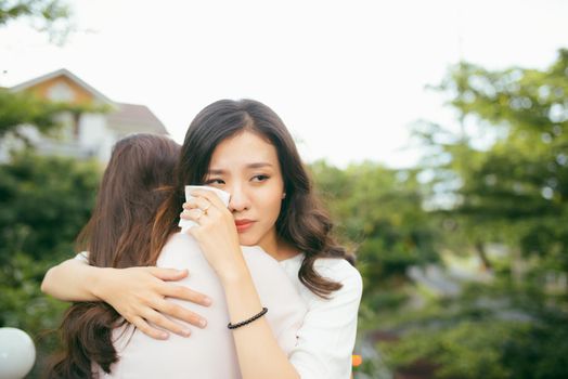 Friendship help support. Depressed asian woman embracing her friend.
