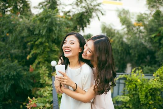 Two Women Relaxing On Rooftop Garden Drinking Coffee