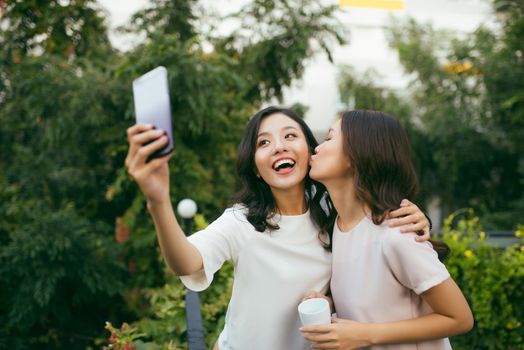 Lifestyle of Two beautiful Happiness Long Hair Women are  Using Mobile Phone for Selfie in Garden. Asian Female Models Portrait Concept.