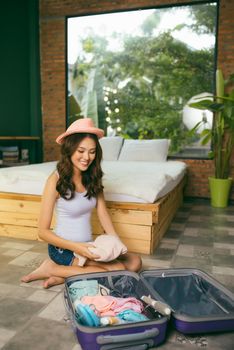 Travel and vacation concept, happiness woman packing stuff and a lot of clothes into suitcase on bed prepare for her travel and journey trip.