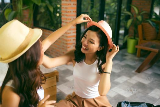 Two happy young women while packing suitcases at home for vacation or trip