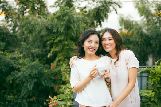 Two beautiful young well-dressed women chatting outdoors over coffee