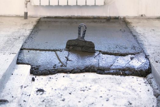 A trowel in a layer of fresh concrete on the floor