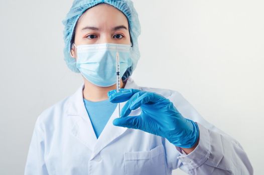 Closeup vial of covid-19 vaccine in hand of professional scientist or doctor in laboratory for treatment with mask gloves and lab coat on white background. Health business and industry concept.