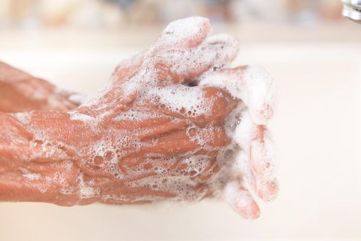 senior women washing hands with soap warm water .