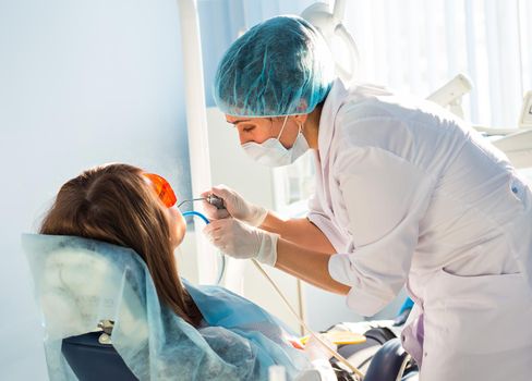 Woman dentist working at her patients teeth.