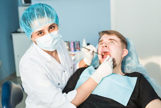 Woman dentist working at her patients teeth.