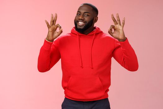 Guy promise perfection. Portrait confident charismatic pleasant african american man show okay no problem gesture say okay smiling assuring everything cool, standing pink background delighted.