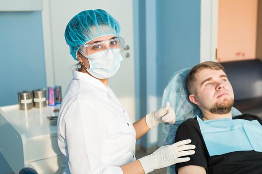 people, medicine, stomatology and healthcare concept - happy young female dentist with tools over medical office background.