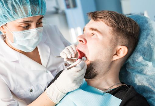 Woman dentist working at her patients teeth.