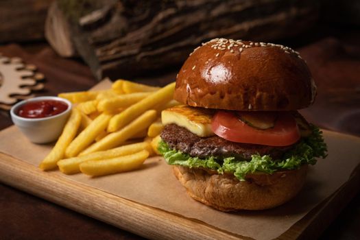 Beef burger served with french fries decorative wooden desk and tomato sauce in the sauce bowl. Restaurant concept. Fast food concept. Street food concept.