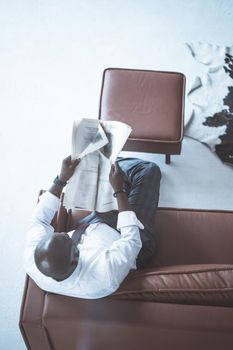 Owner of a Large Company Sits on the Couch and Looks Through the Morning Newspaper in his Modern Office. Close-up. Top View. High quality photo