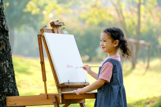 Lovely little girl show happy smile and enjoy with painting in the garden with morning light.