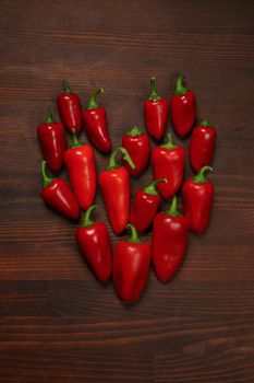 Fresh heart of chillies or peppers and capsicums or bell peppers. Sweet bell, paprika, cayenne, Hungarian wax pepper, isolated on wooden table background. Vertical photo. Top view.