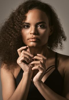 Close up African American girl with afro hair standing in black bare shoulder top isolated on grey background. Human emotions, facial expression concept.