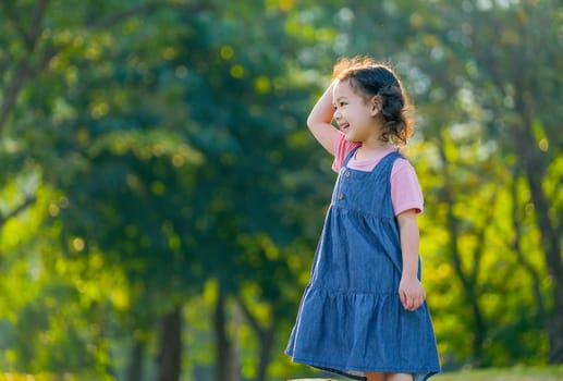 Young Asian little girl play alone in the garden with morning light.