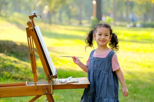 Lovely little girl show happy smile and enjoy with painting in the garden with morning light.