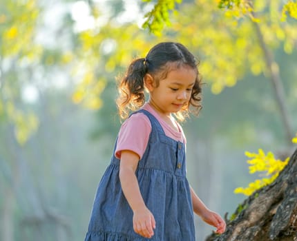 Young Asian little girl play alone in the garden with morning light.