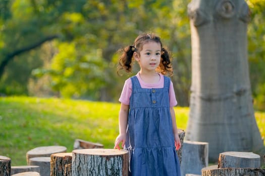 Young Asian little girl play alone in the garden with morning light.