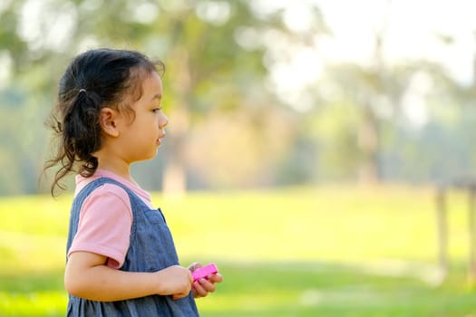 Close up on side of little girl enjoy with playing in the green garden with morning light and copy space.